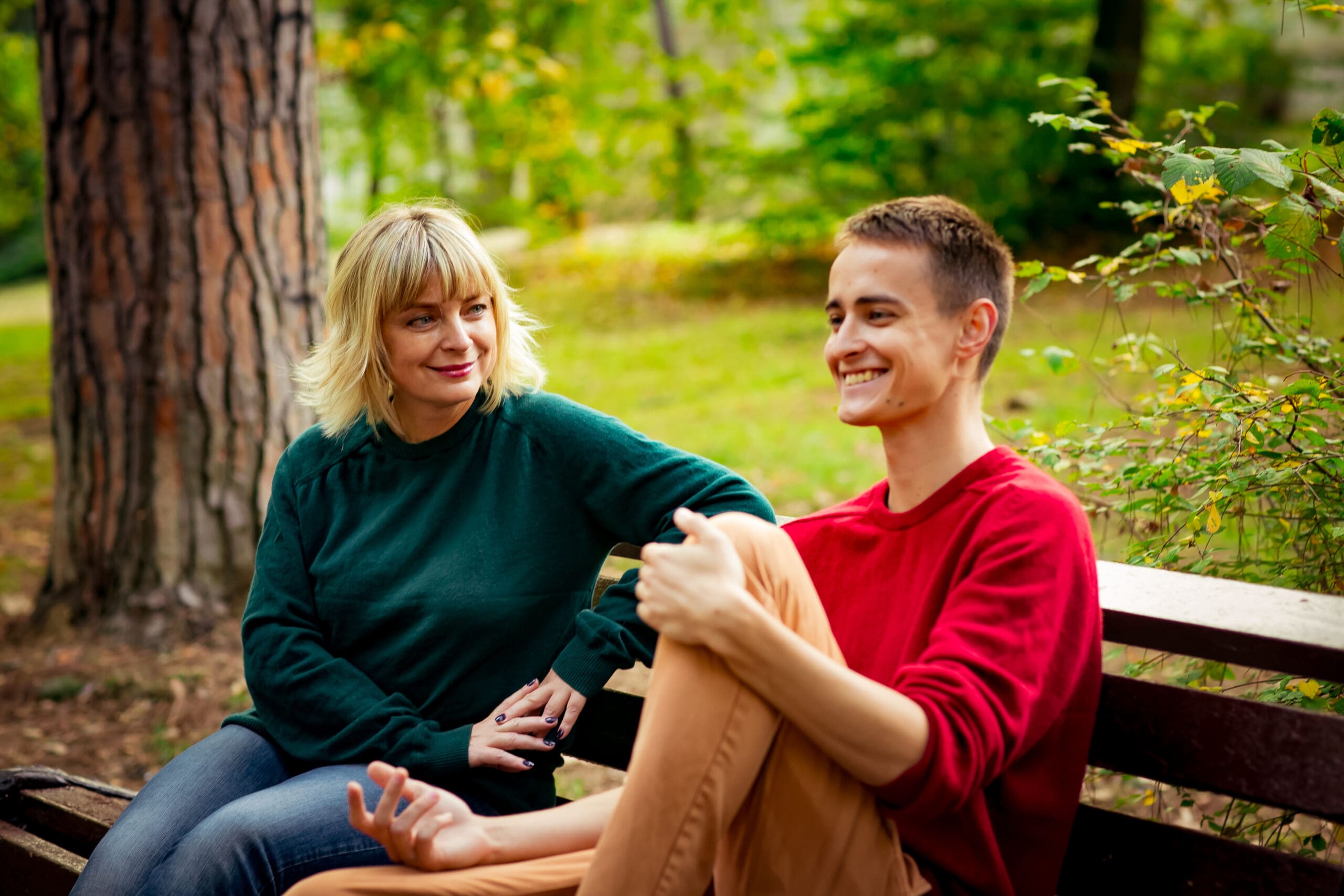 Beautiful woman,blonde,middle-aged,with her son,sitting on a bench in the Park, and communicate